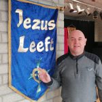 Richard met op de achtergrond een banner met de tekst 'Jezus Leeft'